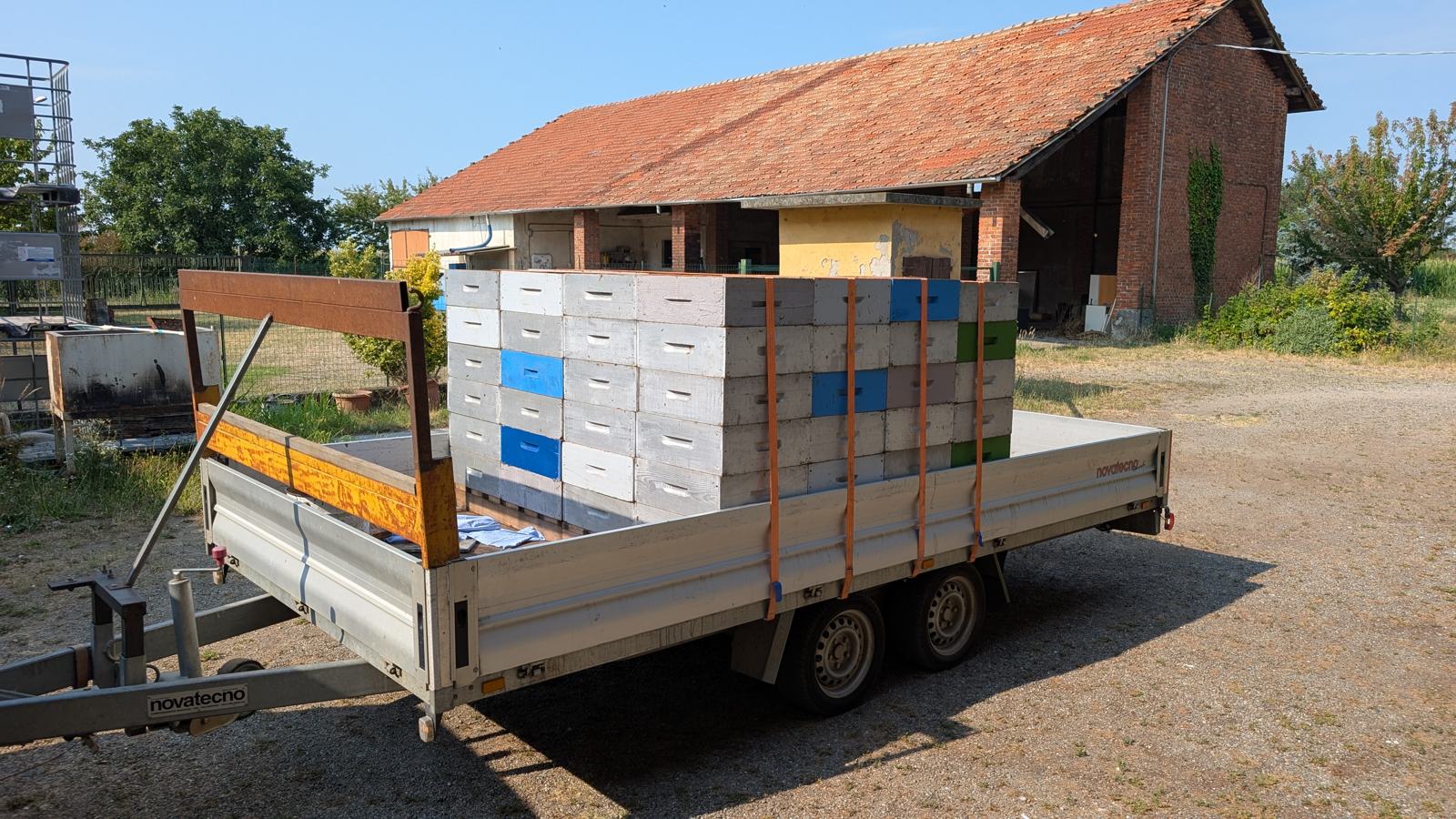Carrello carico di melari fissati con cinghie davanti alla cascina